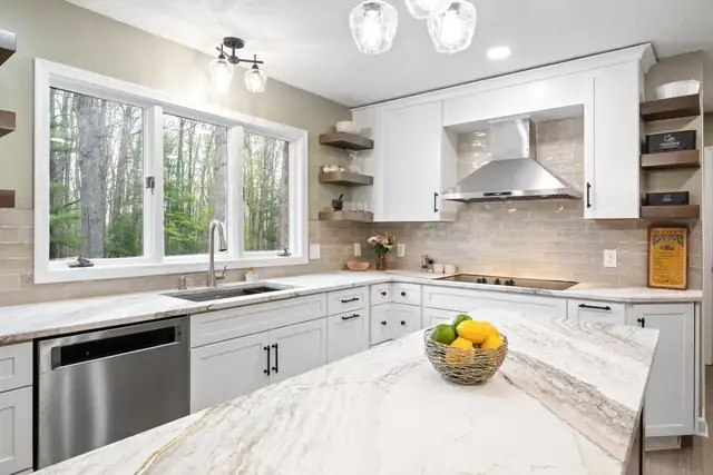 Blacksburg kitchen with white cabinets, marble-look island, stainless hood and floating wood shelves