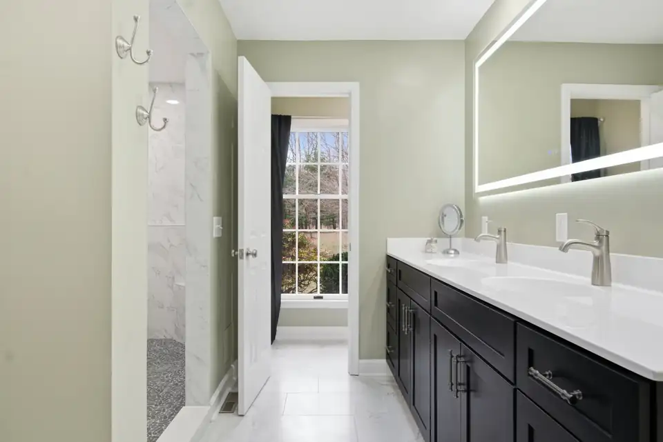 Bathroom remodeling Blacksburg VA: Preston Forest primary bath with black double vanity, white quartz top, lighted mirror and sage walls