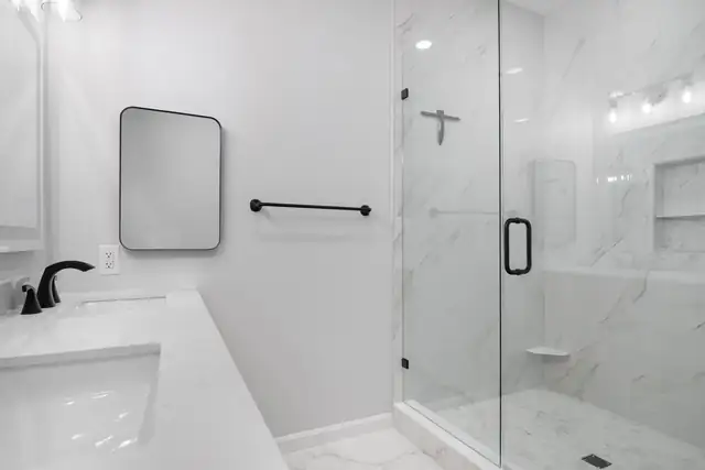 Christiansburg primary bathroom remodel with a frameless glass walk-in shower in marble-look tile and black fixtures