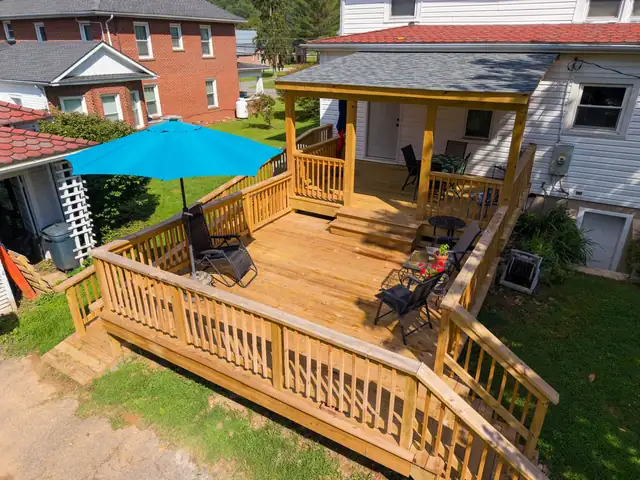 Two-level covered wood deck with an accessible ramp on a 1919 Sears kit house in Pembroke, VA