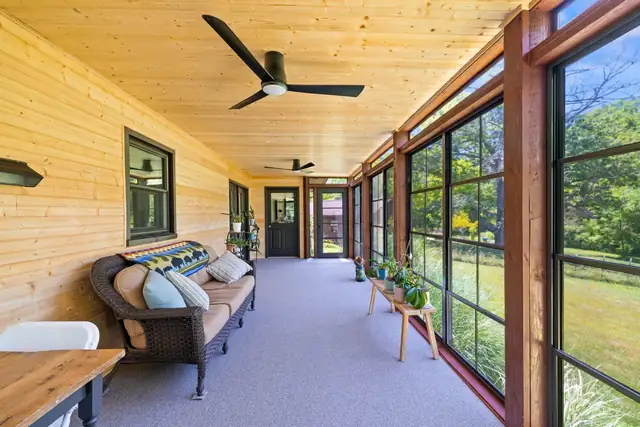 Blacksburg three-season room with knotty pine ceiling and walls, ceiling fans and tall black-framed windows facing the garden