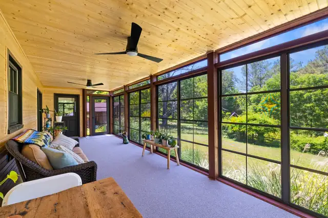 Three-season room in Blacksburg with a pine plank ceiling, ceiling fans and walls of screened windows facing the yard