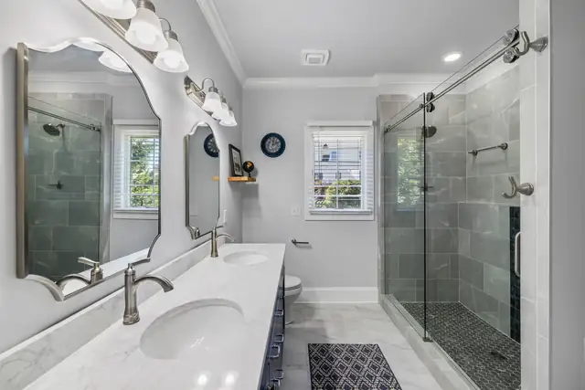 Blacksburg primary bathroom with a rolling glass shower door, gray tile walk-in shower and long vanity